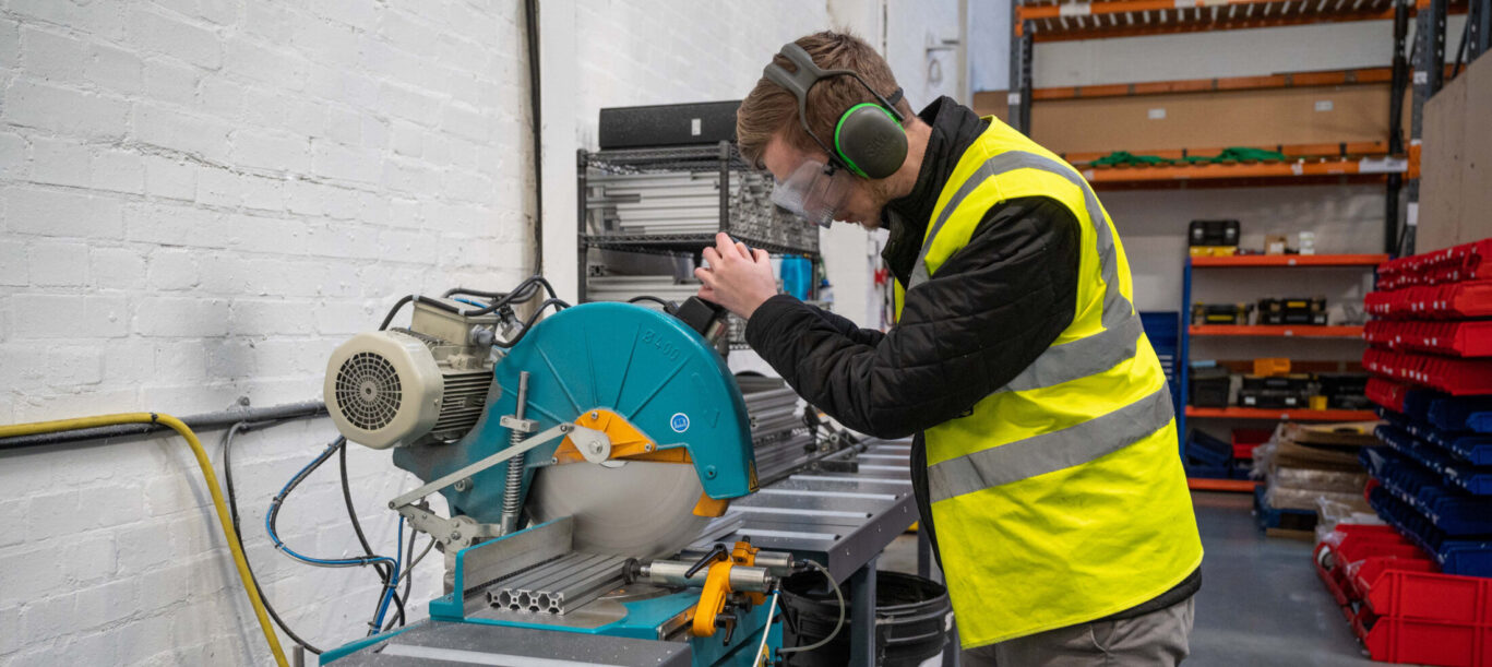 B-Tech technician cutting aluminium mounting components in the workshop