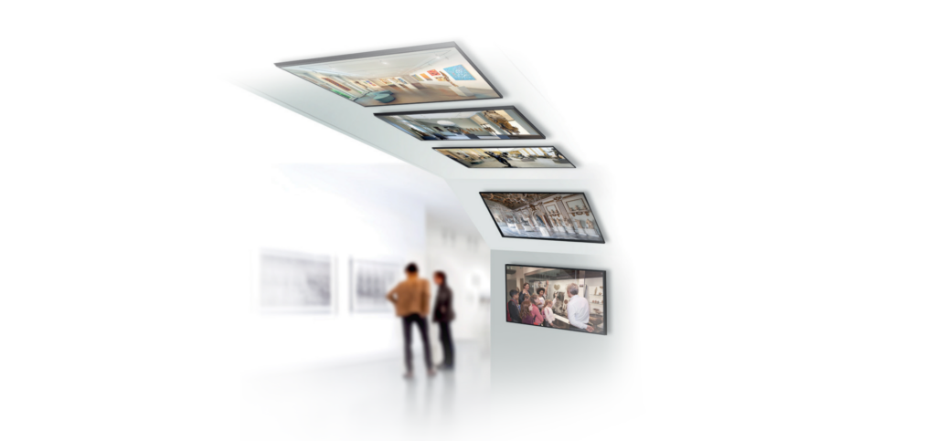 A lifestyle image showing a series of ceiling mounted screens tracking down to an angled wall.